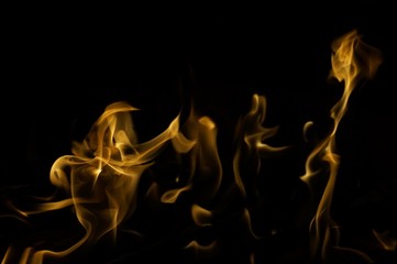 Snapshot of yellow, flickering tongues of fire dancing and twisting on black background