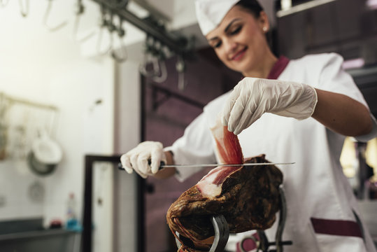 Pretty butchery woman cutting ham.