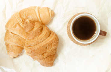 Two baked croissants with a cup of coffee.