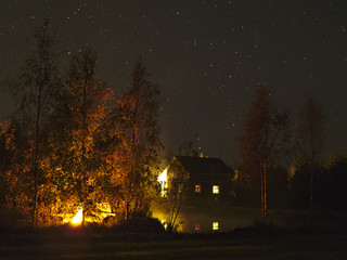 Wilderness cottage by a pond in dark night with starry sky. Finland travel destinations.