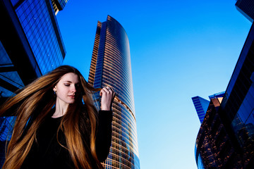 Fototapeta premium Portrait of a beautiful brunette girl with long hair outdoors. Moscow city street fashion