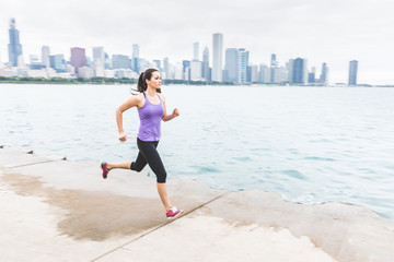 Woman jogging with Chicago skyline on background, panning