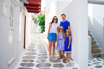 Family vacation in Europe. Parents and kids at street of typical greek traditional village on...