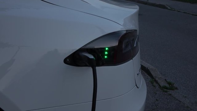 CLOSE UP: Luxury Tesla vehicle filling the batteries in the yard at dawn