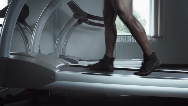 Close up of running male legs on treadmill increase incline