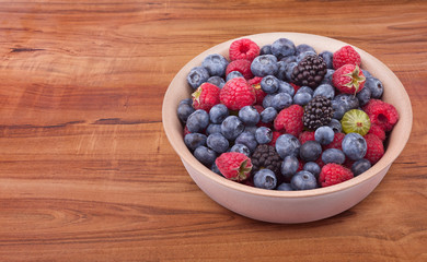 Brown ceramic plate with berries on the wooden table with clipping path
