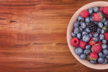 Brown ceramic plate with berries on the wooden table with clipping path