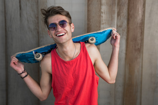 Portrait of cool teenage boy with a skateboard on his shoulder
