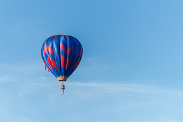 This is a photo of a beautiful hot air balloon slowly sailing through a calm blue sky.