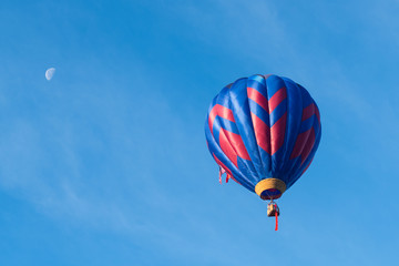 This is a photo of a beautiful hot air balloon slowly sailing through a calm blue sky.