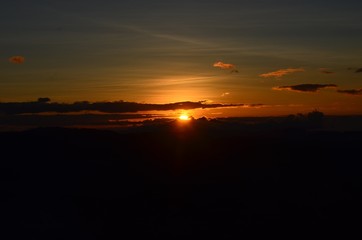 Pôr-do-sol entre nuvens com o céu laranja