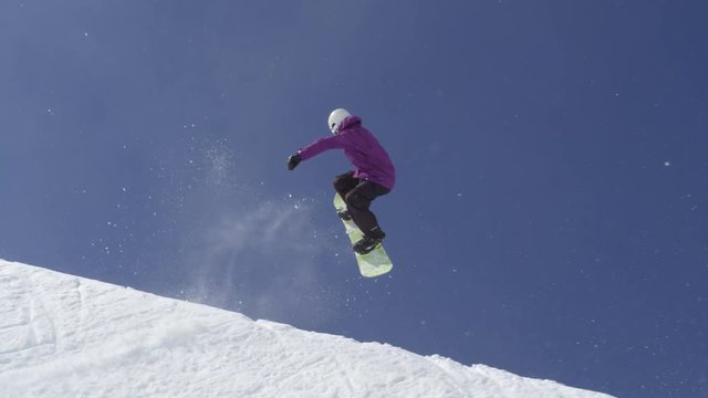 SLOW MOTION: Young pro snowboarder jumping in half pipe in sunny snow park