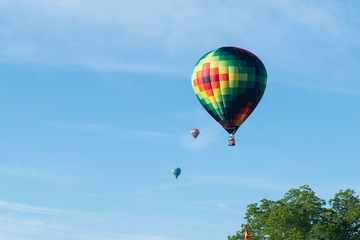 This is a photo of a beautiful hot air balloon slowly sailing through a calm blue sky.