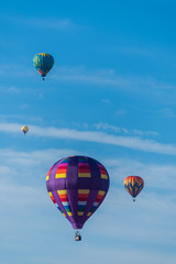 This is a photo of a beautiful hot air balloon slowly sailing through a calm blue sky.