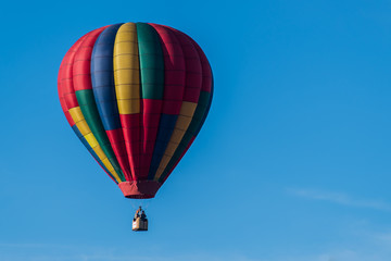 This is a photo of a beautiful hot air balloon slowly sailing through a calm blue sky.