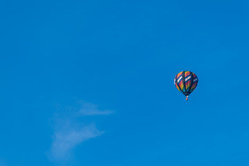 This is a photo of a beautiful hot air balloon slowly sailing through a calm blue sky.