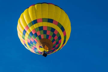 This is a photo of a beautiful hot air balloon slowly sailing through a calm blue sky.