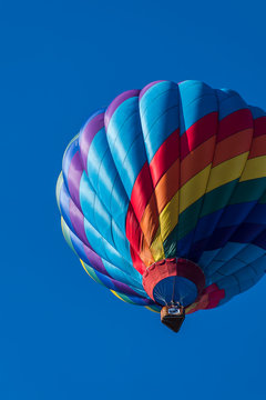 This is a photo of a beautiful hot air balloon slowly sailing through a calm blue sky.