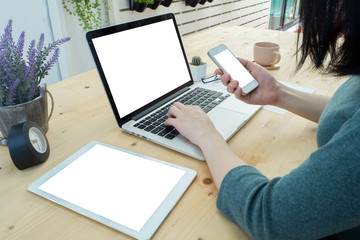 Fototapeta na wymiar Human's hand holding blank screen on smartphone and typing lapto