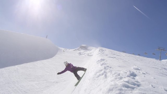 SLOW MOTION: Young pro snowboarder sliding on half pipe wall in sunny snowpark