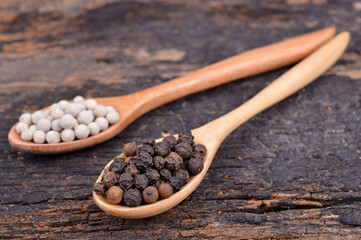 White with black pepper on wood spoon,wooden background.