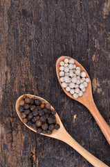 White with black pepper on wood spoon,wooden background.