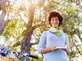 Obraz premium Happy young woman with bicycle reading book