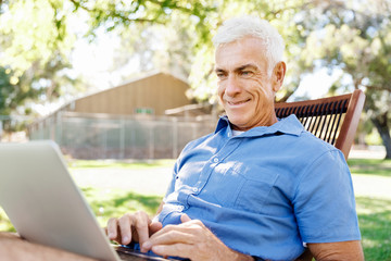 Obraz premium Senior man with notebook sitting in the park