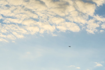 Blue sky with beautiful white clouds and a black small plane.