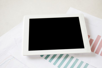 Digital tablet on stock and finance graph papers on desk - with copy space