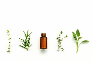 Bottle of essential oil with  fresh herbal sage, rosemary, lemon - 124087531