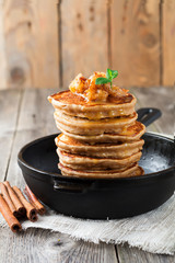 Stack of pancakes from buckwheat flour with baked apples and cinnamon on old wooden background. A healthy breakfast. Selective focus.