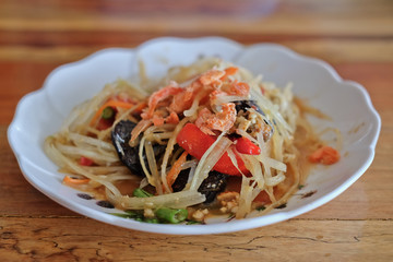 Papaya salad (Som Tam) Thai cuisine spicy delicious on wooden table