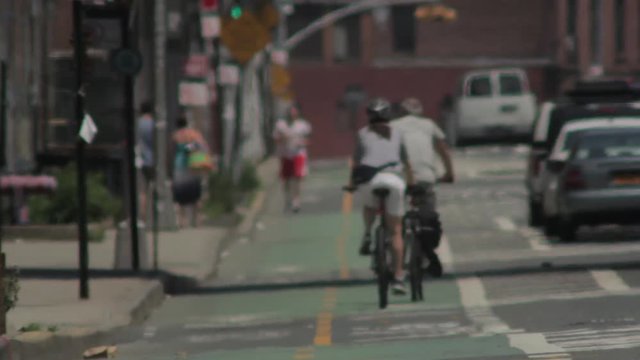 Biking in New York City, couple rides bikes on a bike lane on a hot day with depth of field focus.