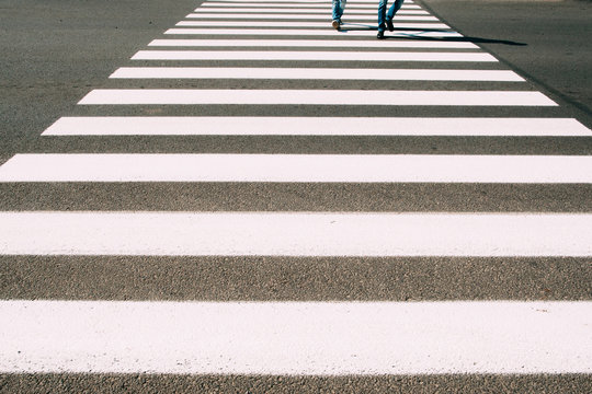 Crossroad with walking people background. Pedestrian zebra on asphalt close-up photo. City street, busy people, safe road crossing concept