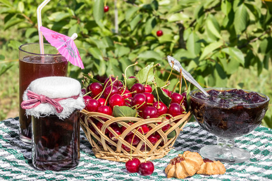 Basket of cherries, cherry jam with biscuit, cherry jam jar and glass of  compote