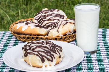Homemade cinnabons cinnamon buns with cream cheese glaze and chocolate icing and  glass of milk