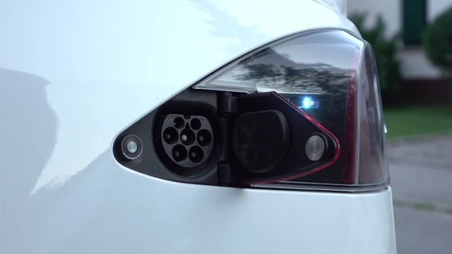 CLOSE UP: Businessman unplugging Tesla electric car from charging station