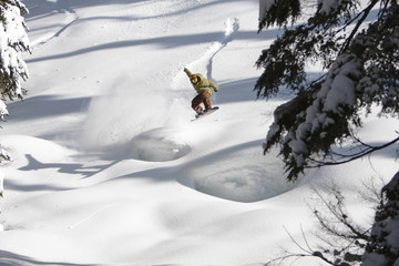 Snowboarder Catching Air off a Natural Jump on a Sunny Winter Day at the Ski Resort