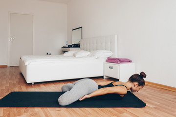 Fit woman doing yoga on mat at home in the bedroom. lifestyle concept