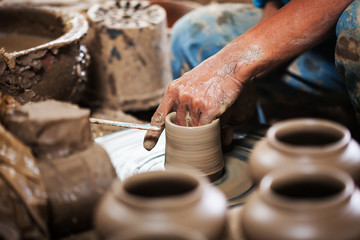 dirty hands making pottery in clay on wheel