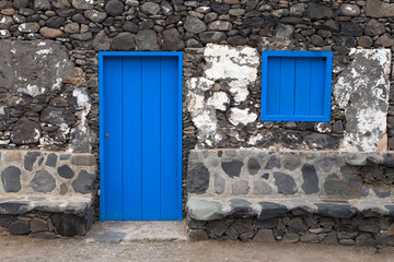 blue door and hatch in a simple house made of black boulders