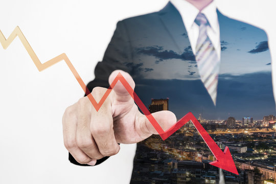 Businessman pointing finger to screen with a falling dow to bottom arrow graph, representing business decrease