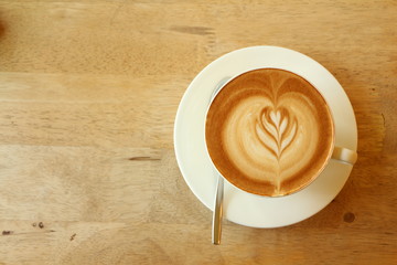 Hot latte in white cup on wood background.