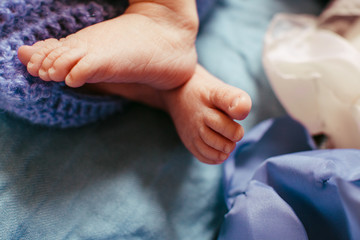 Tiny child's feet hang over the blue bed