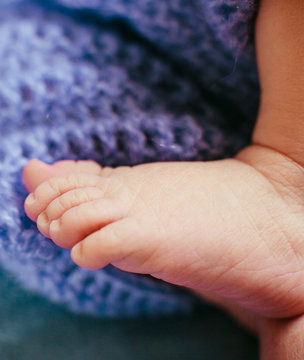 Pink feet of newborn kid lying on the blue woolen blanket