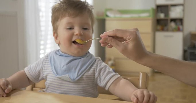 POV shot of an adorable playful baby being fed with baby food. 
