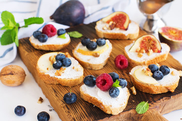 Small bruschetta with berries, honey, ricotta and mint