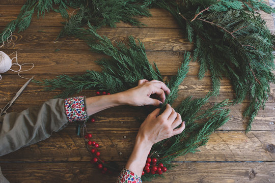 Florist at work: Creating a wooden wreath with christmas red ba