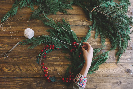 Florist at work: Creating a wooden wreath with christmas  red ba